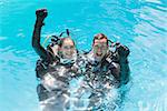 Smiling couple on scuba training in swimming pool looking at camera on a sunny day