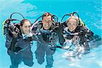 Smiling friends on scuba training in swimming pool looking at camera on a sunny day