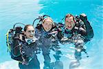 Smiling friends on scuba training in swimming pool cheering at camera on a sunny day