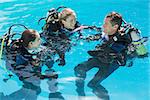 Smiling friends on scuba training in swimming pool on a sunny day
