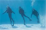 Three friends on scuba training submerged in swimming pool on their holidays