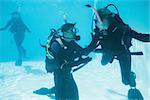 Friends on scuba training submerged in swimming pool on their holidays
