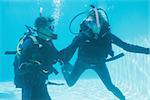 Friends on scuba training submerged in swimming pool  on their holidays