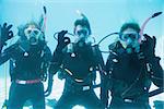 Friends on scuba training submerged in swimming pool looking to camera  on their holidays