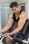 Focused bodybuilder lifting heavy black barbell at the gym