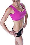Female bodybuilder posing in pink sports bra and shorts on white background