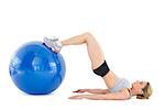 Fit woman lying on floor with legs on exercise ball on white background