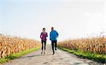 Adult couple running on country road, Germany