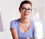 Portrait of young woman in office, wearing horn-rimmed eyeglasses and looking at camera, Germany