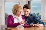 Teenage boy with grandmother working on tablet computer, Germany