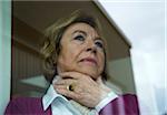 Portrait of senior woman looking out of window at home, Germany
