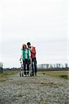 Teenage grandson with grandmother using walker on pathway in park, walking in nature, Germany