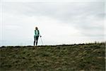 Senior woman walking along path using crutches, in nature, Germany