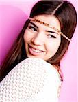 Close-up portrait of young woman with long, brown hair, wearing headband, smiling and looking to the side, studio shot on pink background