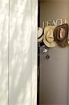 Assorted hats hang on coat hooks at entrance to beach house holiday home
