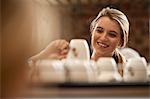 Young female waitress picking up cup from tray in cafe