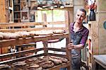 Portrait of young male baker with shelves of fresh bread