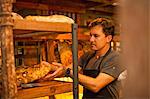 Mature man placing fresh bread on shelf