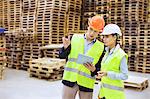 Male and female managers using digital tablet in distribution warehouse