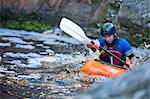 Mid adult man kayaking on river rapids