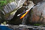 Mid adult man kayaking down river waterfall