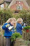 School boy and girl watering plants in garden