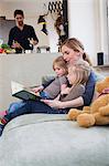 Mother and two daughters reading storybook