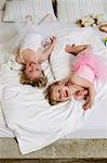 Portrait of two young sisters playing on bed