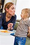 Mid adult mother eating spaghetti with her daughter