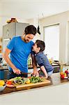 Father and young son preparing vegetables in kitchen