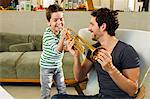 Father encouraging young son playing trumpet