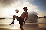 Mid adult man playing keepy uppy on Botafogo beach, Rio De Janeiro, Brazil