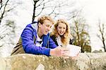 Teenage brother and sister looking at digital tablet on rural bridge