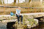 Unhappy teenage boy looking down from rural bridge