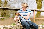 Teenage boy sitting on footbridge with his jack russell dog