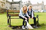 Teenage brother and sister watching duck from bench