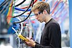 Mid adult male technician testing cables in engineering plant