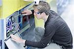 Mid adult male technician maintaining equipment in engineering plant