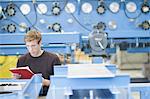 Mid adult male technician checking paperwork in engineering plant