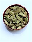 A bowl of green cardamoms on a white background