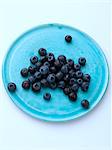 Ripe blueberries on a turquoise plate on a white background