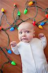 Baby lying on floor surrounded by christmas lights