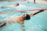 Swimmers racing in backstroke in pool