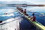 Rowing team rowing scull on lake