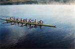 Rowing crew rowing scull on lake