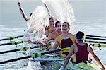 Rowing team splashing and celebrating in scull on lake