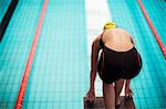 Swimmer poised at starting block above pool