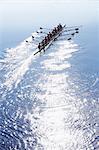 Rowing team rowing scull on sunny lake