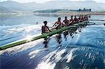 Rowing team rowing scull on lake