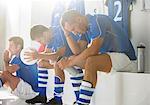 Disappointed soccer players sitting in locker room